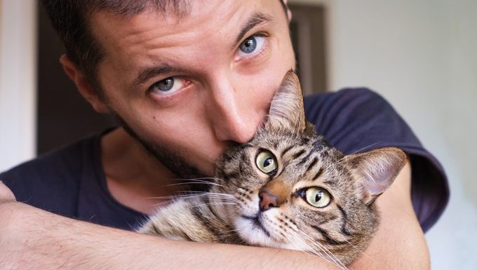 man hugs cat