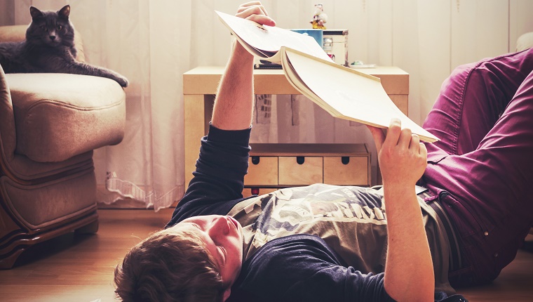 Caucasian man reading on living room floor