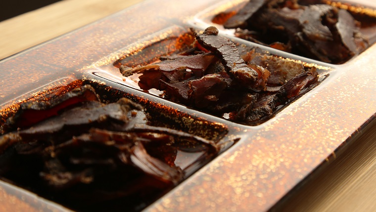 Biltong (dried meat) on a wooden board, this is a traditional food snack that can be found in South Africa.