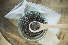 Chiasamen in einem Holzlöffel und Vorratsglas auf rustikalem Holztisch