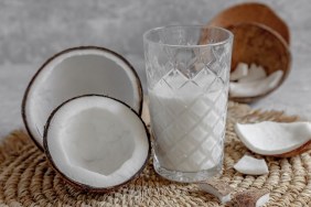 Opened coconuts, glass of homemade coconut milk and coconut chunks