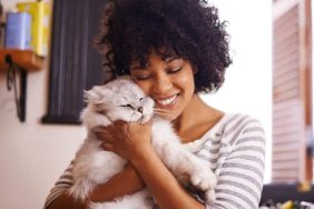 woman hugging cat while cat sitting