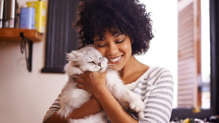 woman hugging cat while cat sitting